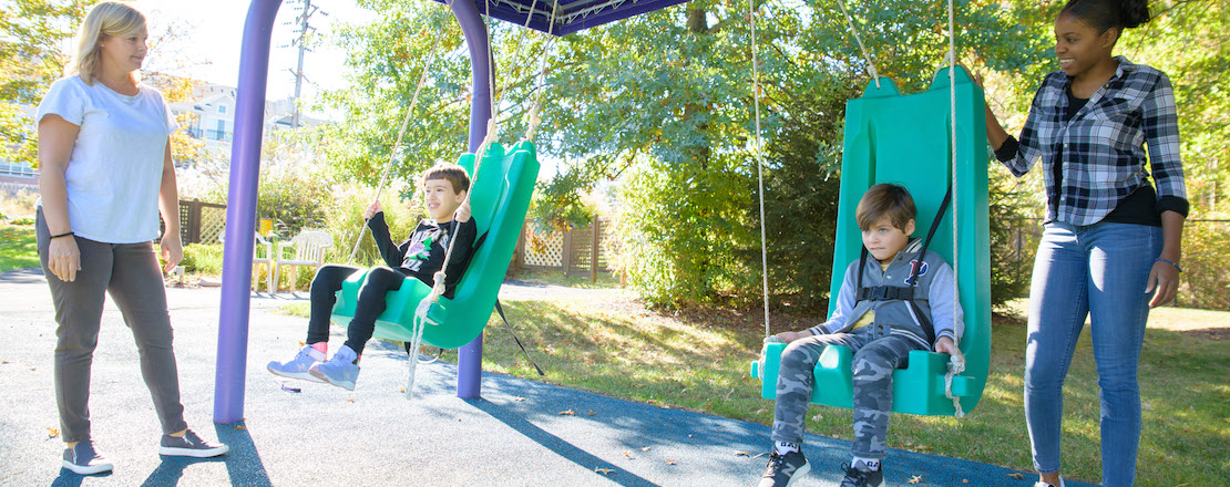 Two teachers with two students on swings