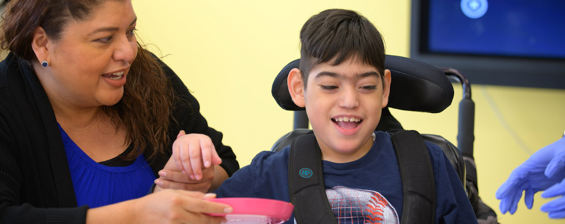 Boy smiling in wheelchair with teacher