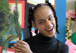 Student smiling holding pine branch