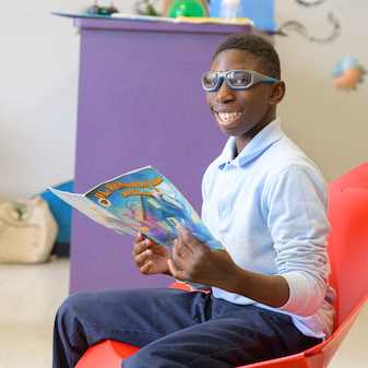 Student smiling and reading a book