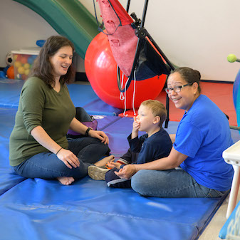 Two therapists on mat with student